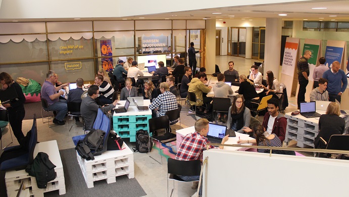 Metropolia students sitting in small groups at tables in the lower lobby of Helsinki City Hall.